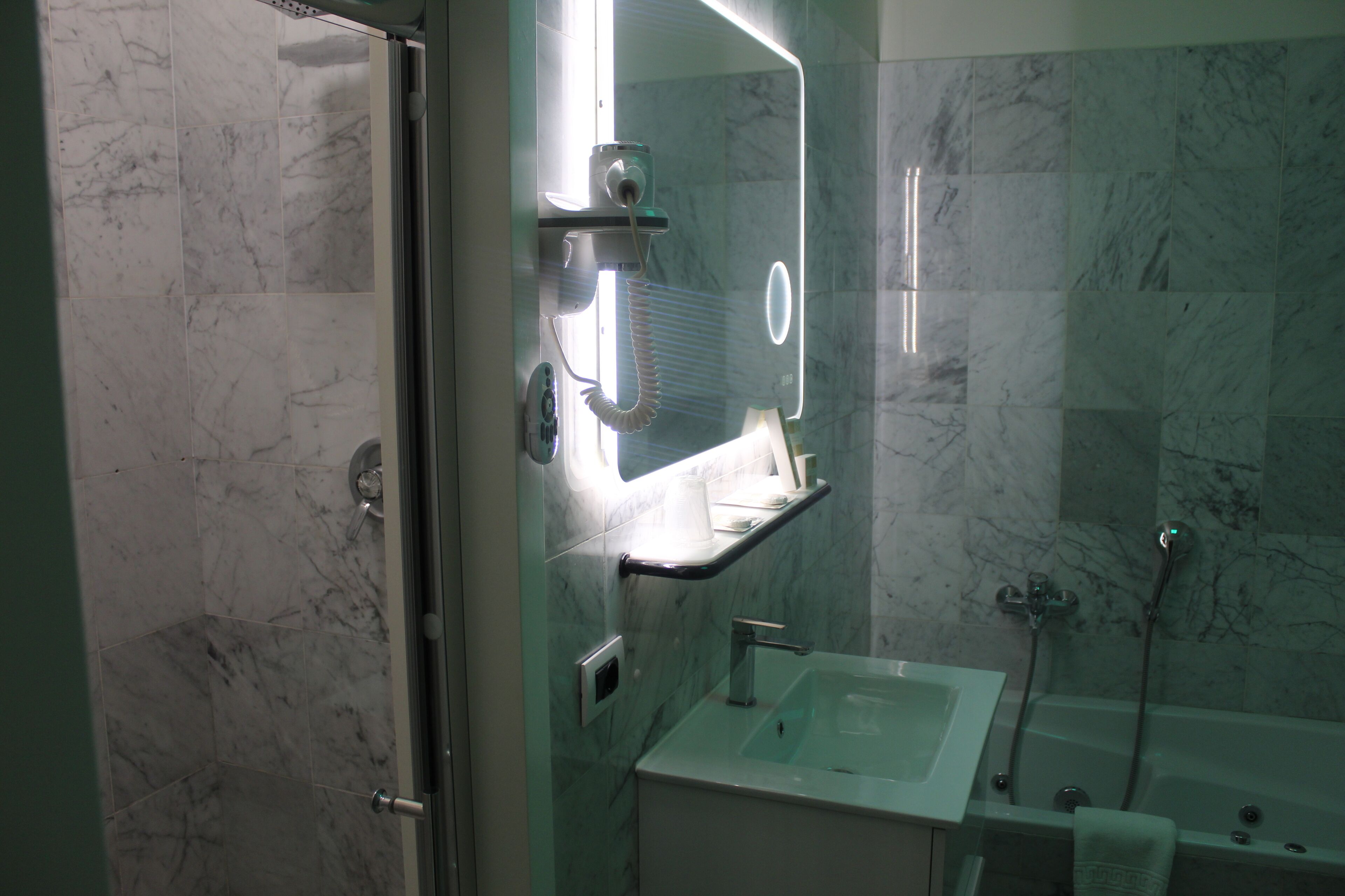 Ein Badezimmer mit Glasdusche, Waschbecken mit Spiegel darüber und einer Badewanne.