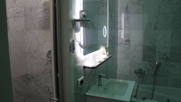 Ein Badezimmer mit Glasdusche, Waschbecken mit Spiegel darüber und einer Badewanne.