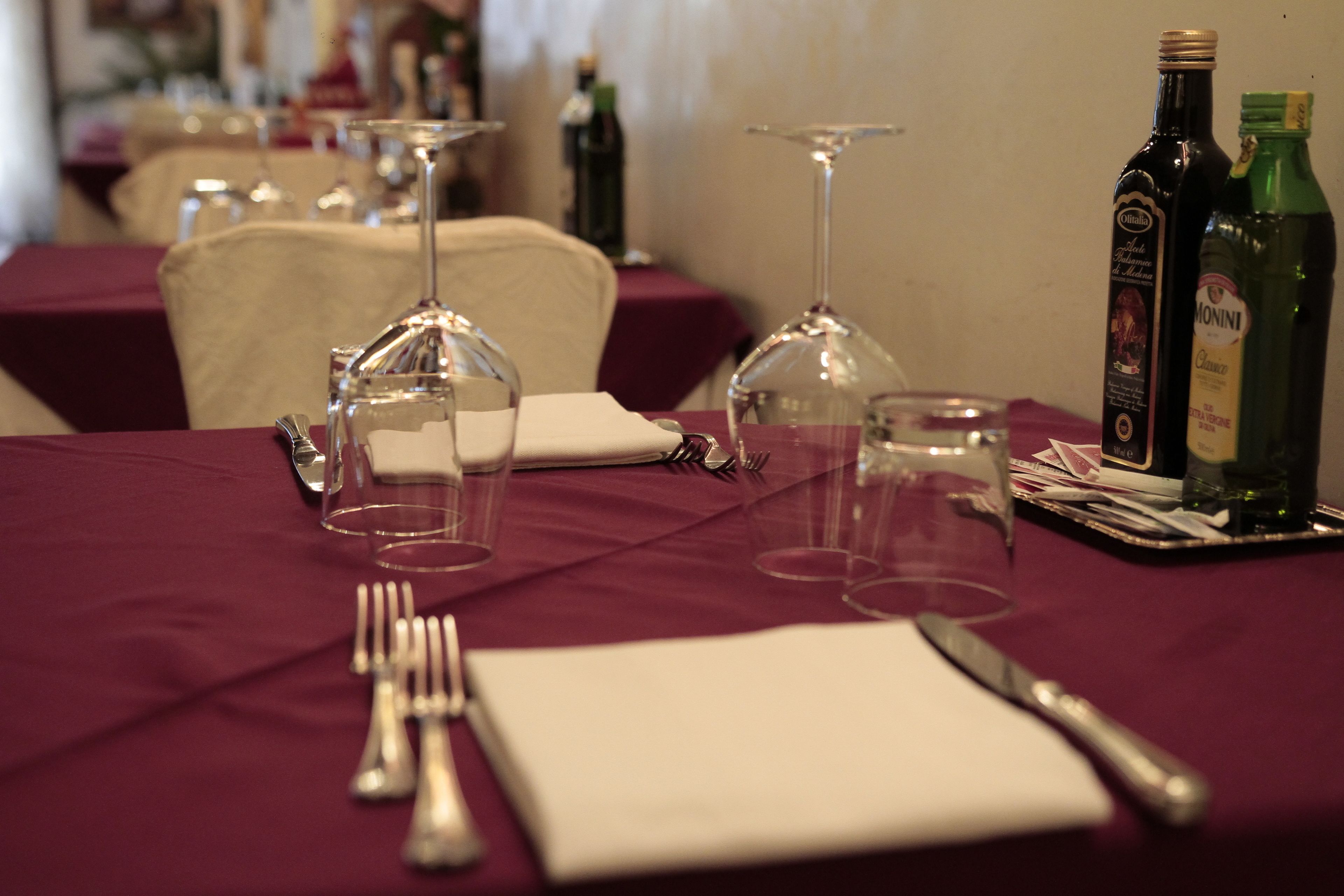 A dining table set with wine glasses, cutlery, and bottles.