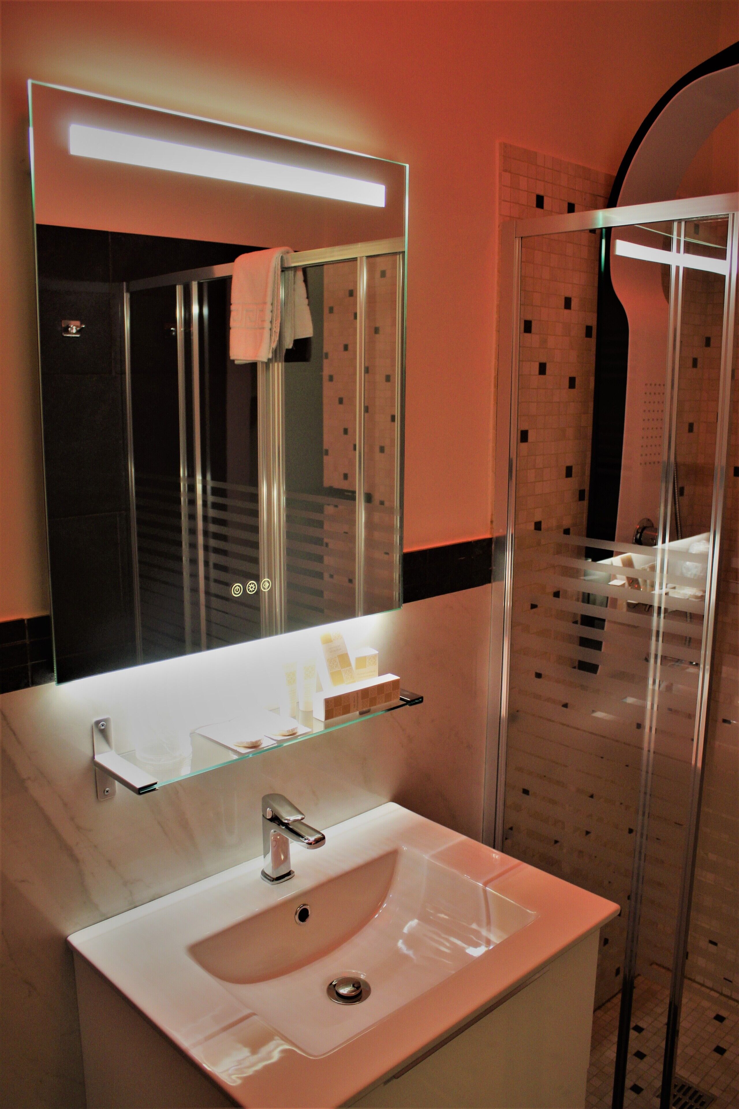 A bathroom with a white sink, a mirror, and a glass-enclosed shower.