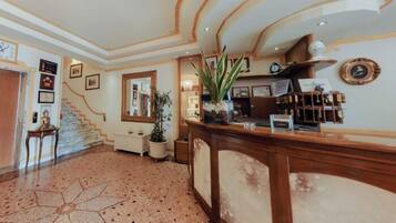 Eine Empfangshalle mit einer Rezeption, einer Treppe und einem großen Spiegel.