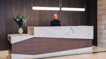 A reception desk with a marble top, wooden paneling on the walls, and a vase of flowers on the left.