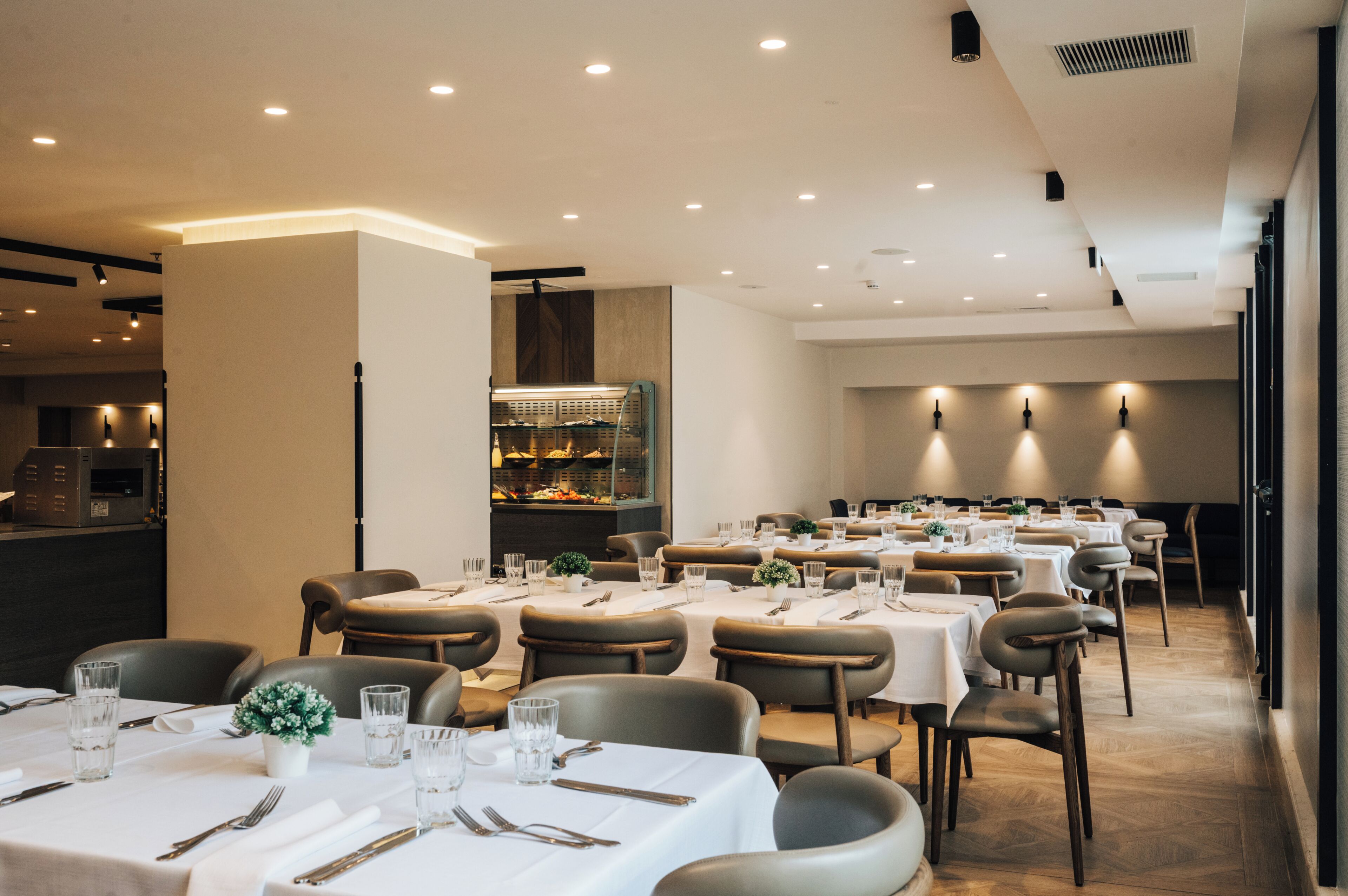 Un restaurante con varias mesas y sillas, una zona de buffet y una decoración interior moderna.