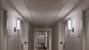 A long, narrow hallway with wooden flooring and a dark patterned carpet, flanked by white walls and doors with light fixtures. - Skyline Hotel Jerusalem (Jerusalem)