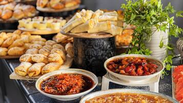 Variedad de pasteles y platos en una mesa, junto con un jarrón decorativo grande con follaje.