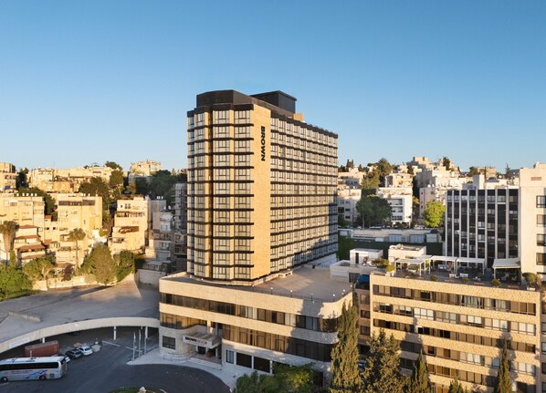 Un immeuble à plusieurs étages doté d’une architecture moderne, avec une entrée imposante et un espace de stationnement.