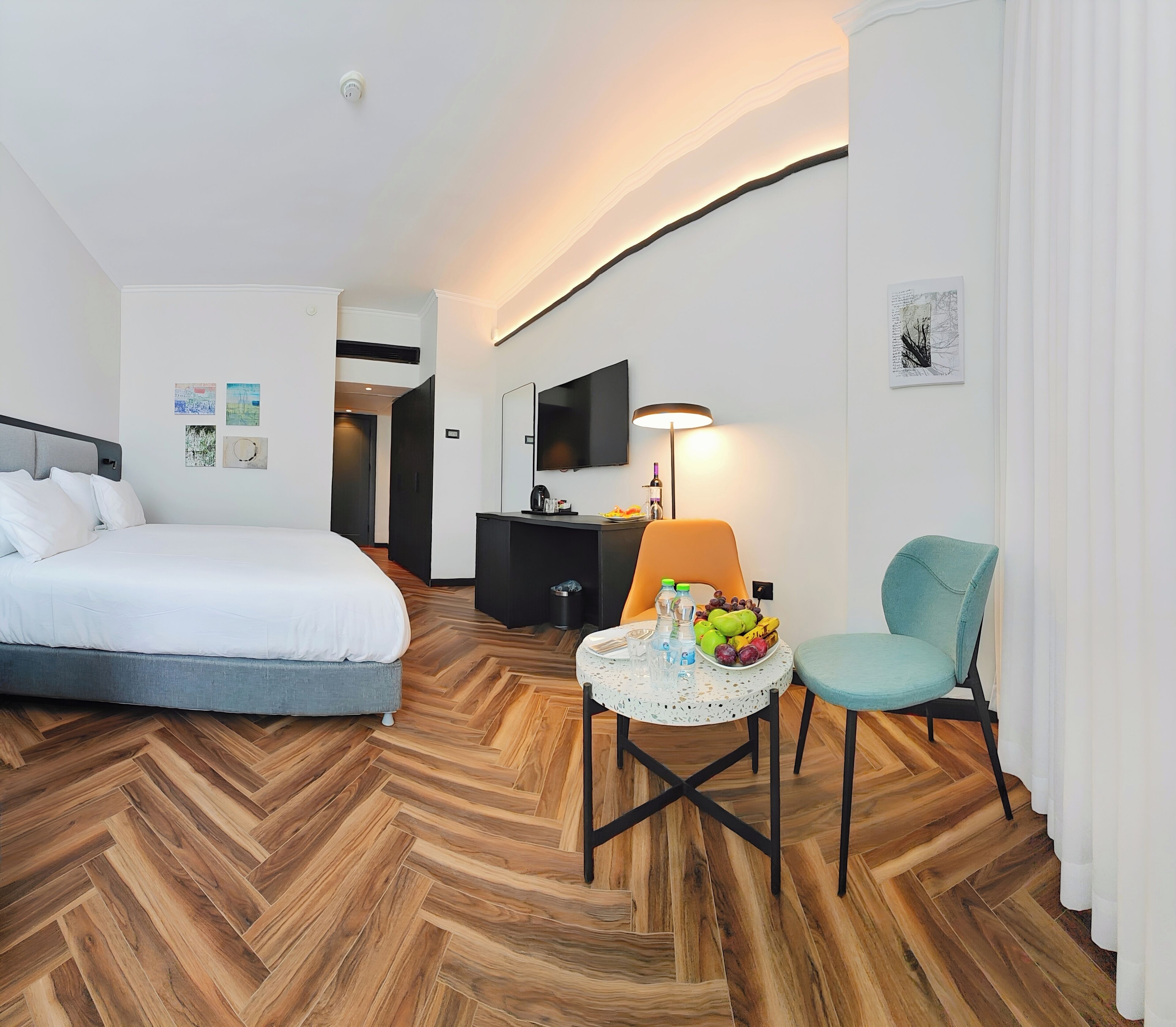 Ein Hotelzimmer mit einem Bett, einem Schreibtisch, einem Stuhl und einem kleinen Tisch mit Früchten.