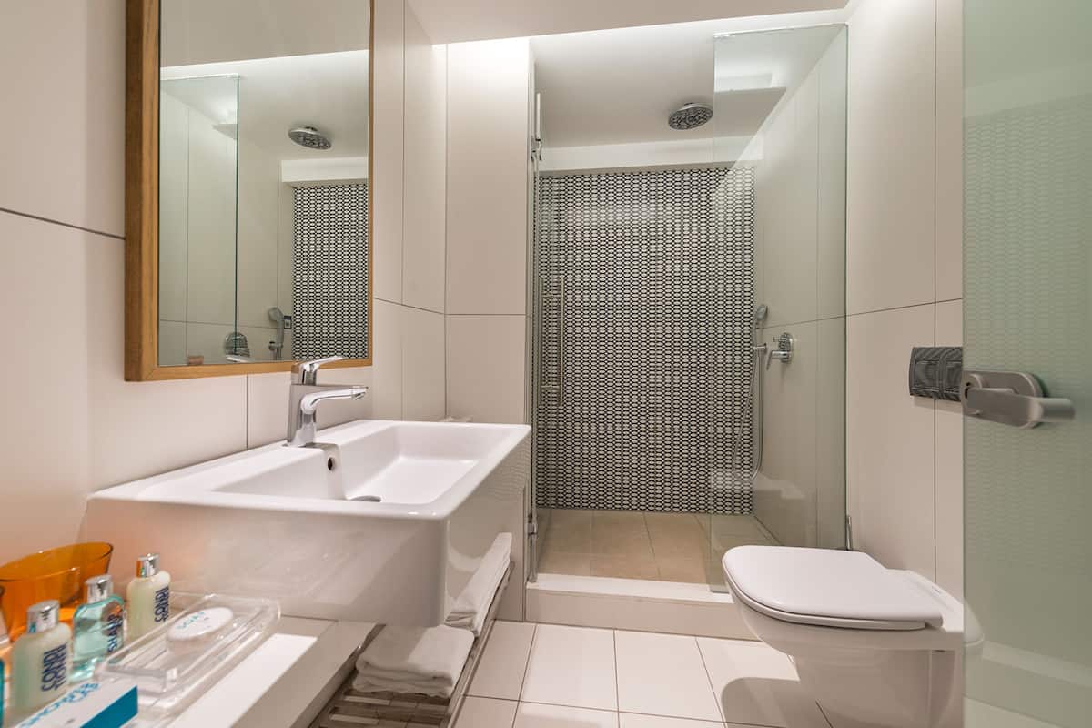A modern bathroom with a white sink, a glass shower enclosure, and a toilet.