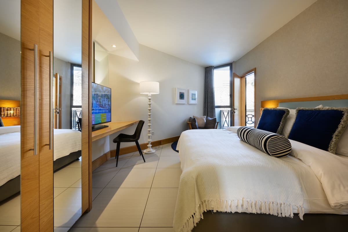 A hotel room with a bed, a desk, a chair, a TV, and a window.