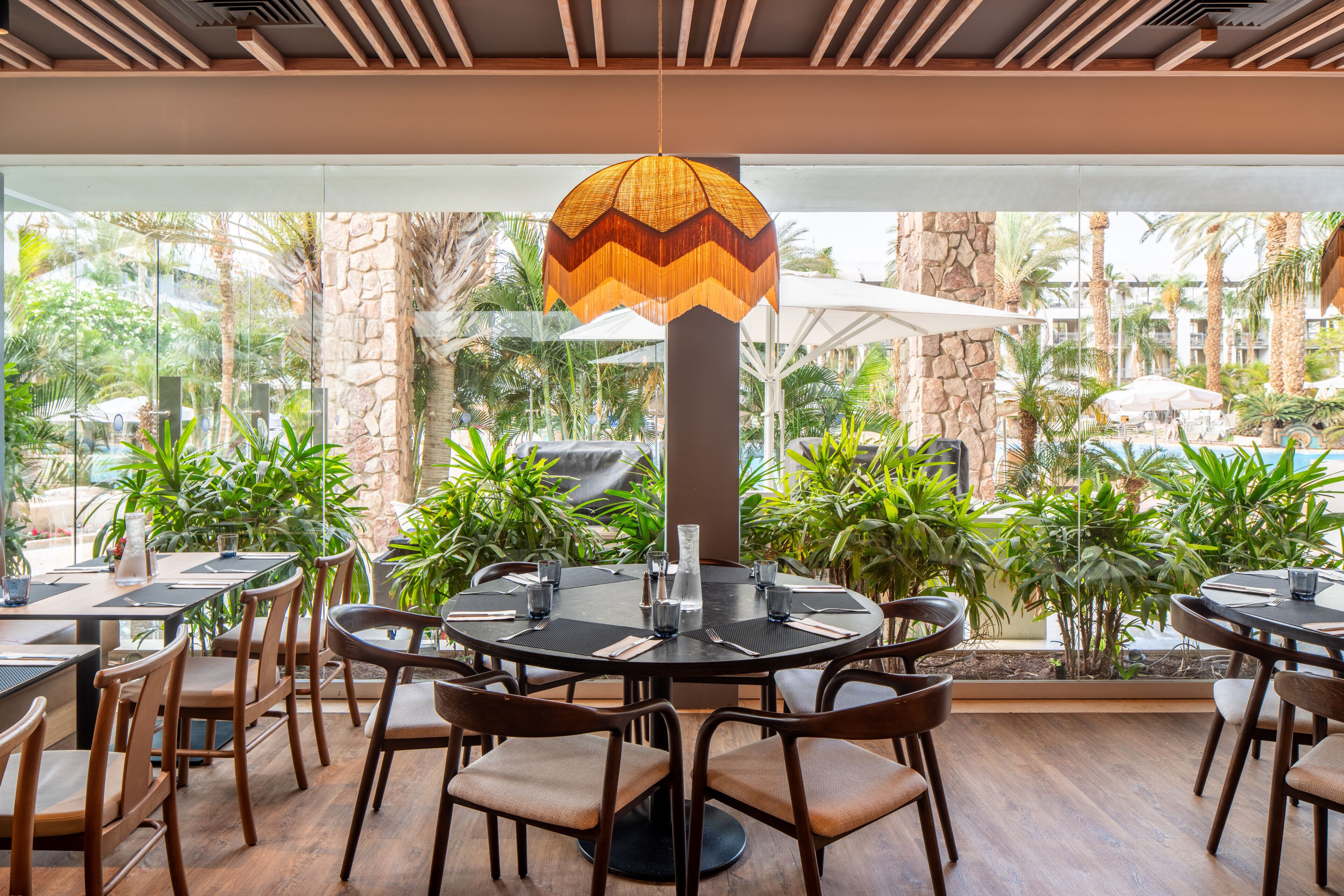 A restaurant with round tables, chairs, and a hanging light fixture.