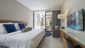 Ein Hotelzimmer mit Bett, Schreibtisch, Fernseher und einem Balkon mit Blick ins Freie.