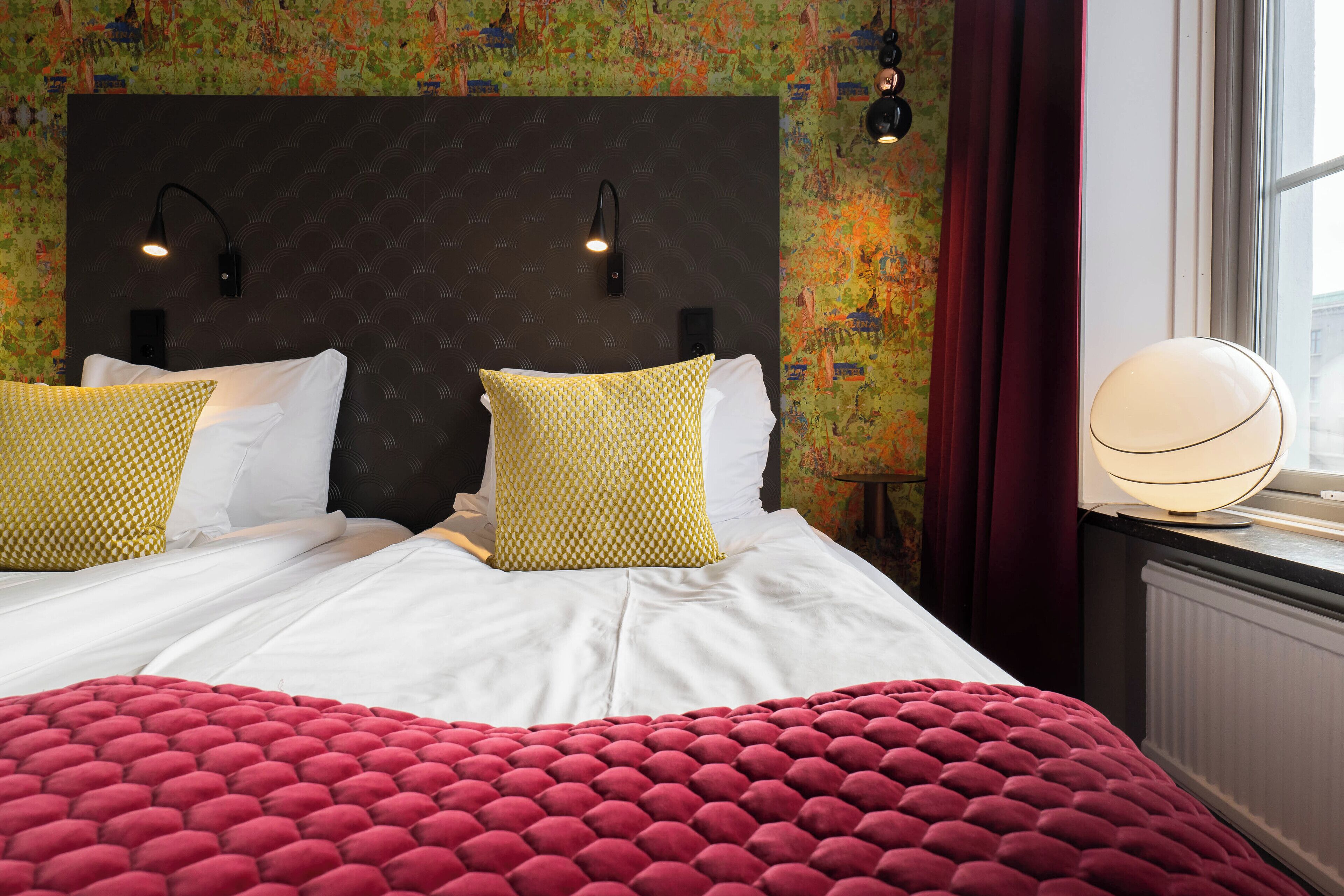 Habitación de hotel con una cama grande, dos lámparas de noche y una ventana con cortinas.