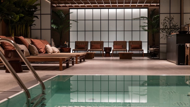 Un espace piscine aménagé avec des sièges et offrant une vue sur une pièce de style japonais traditionnel en arrière-plan.