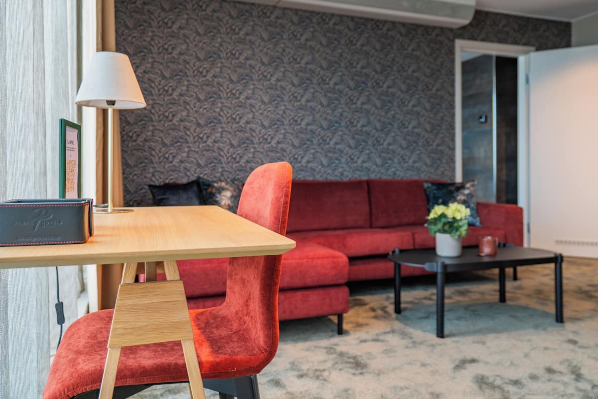 A modern living room with a red sofa, a wooden coffee table, and a lamp.