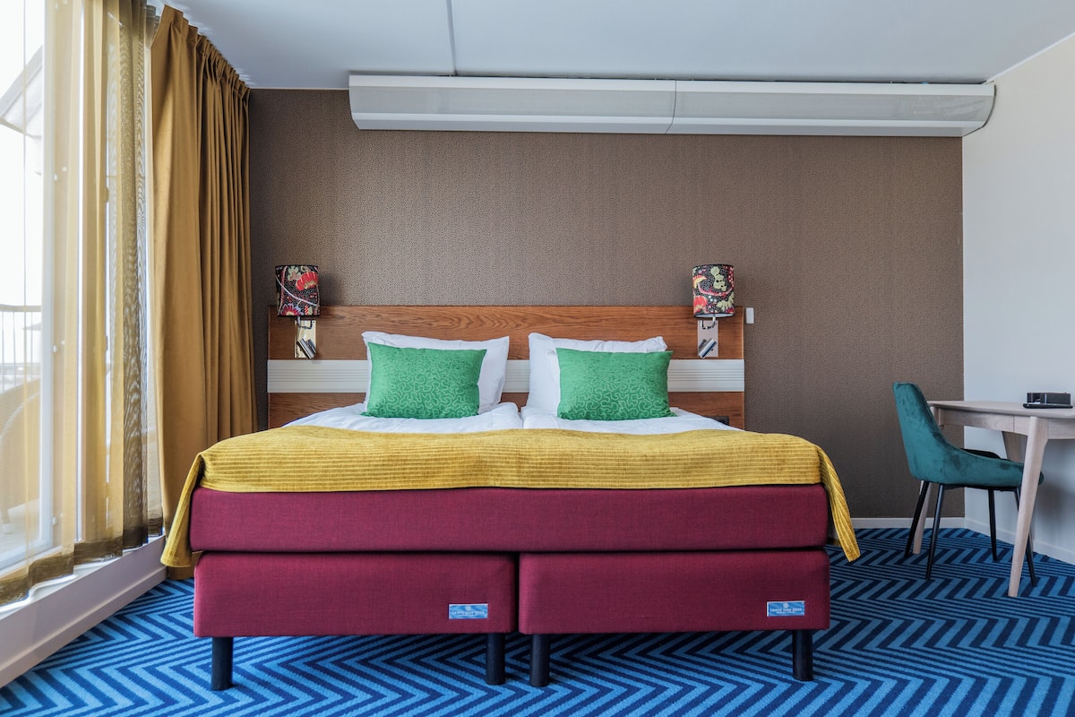 A hotel room with a bed, a desk, and a chair.