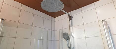 A shower with a handheld showerhead and a wall-mounted faucet in a tiled room.
