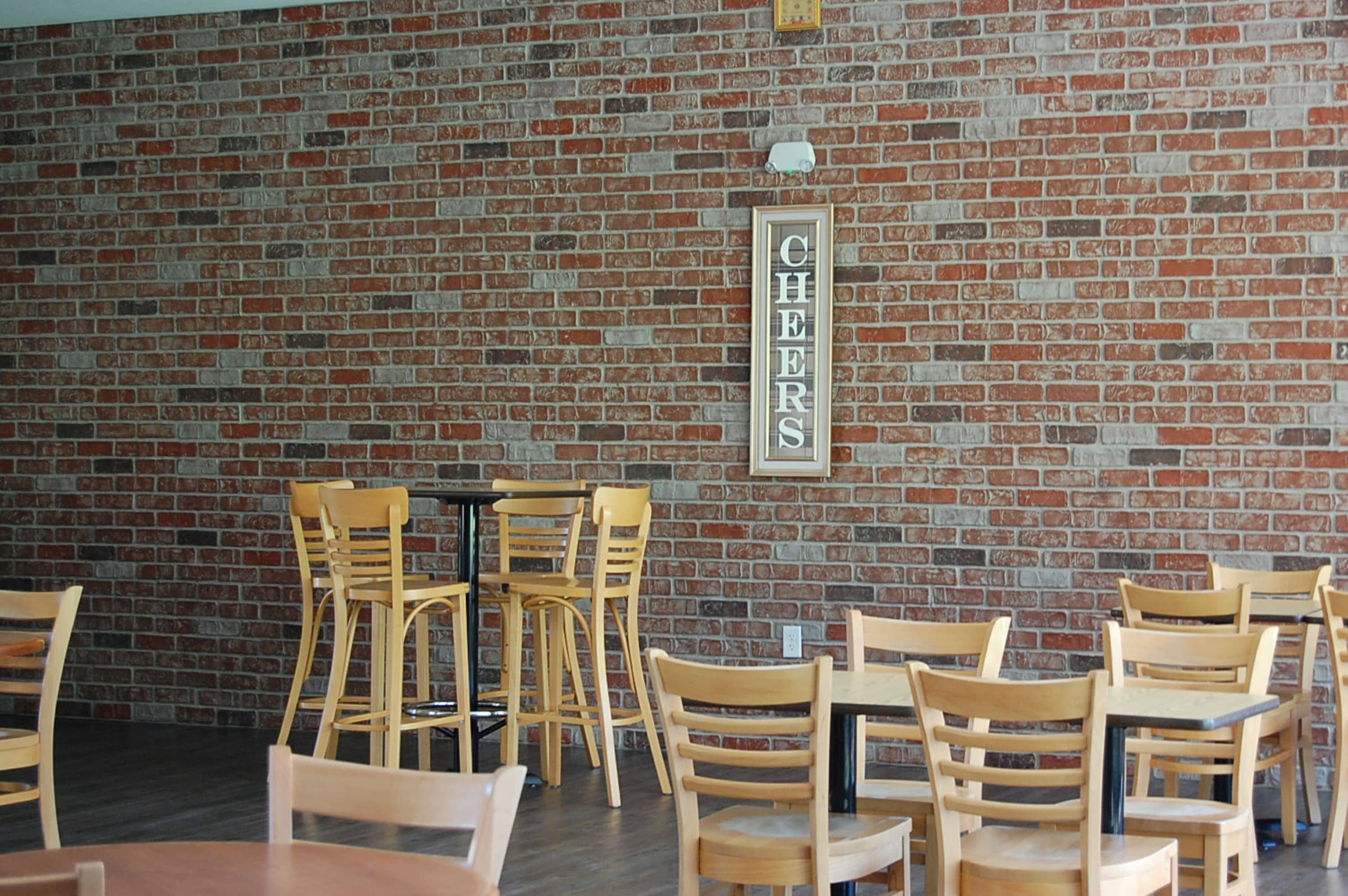 Ein Restaurant mit Backsteinwänden, Holztischen und -stühlen.