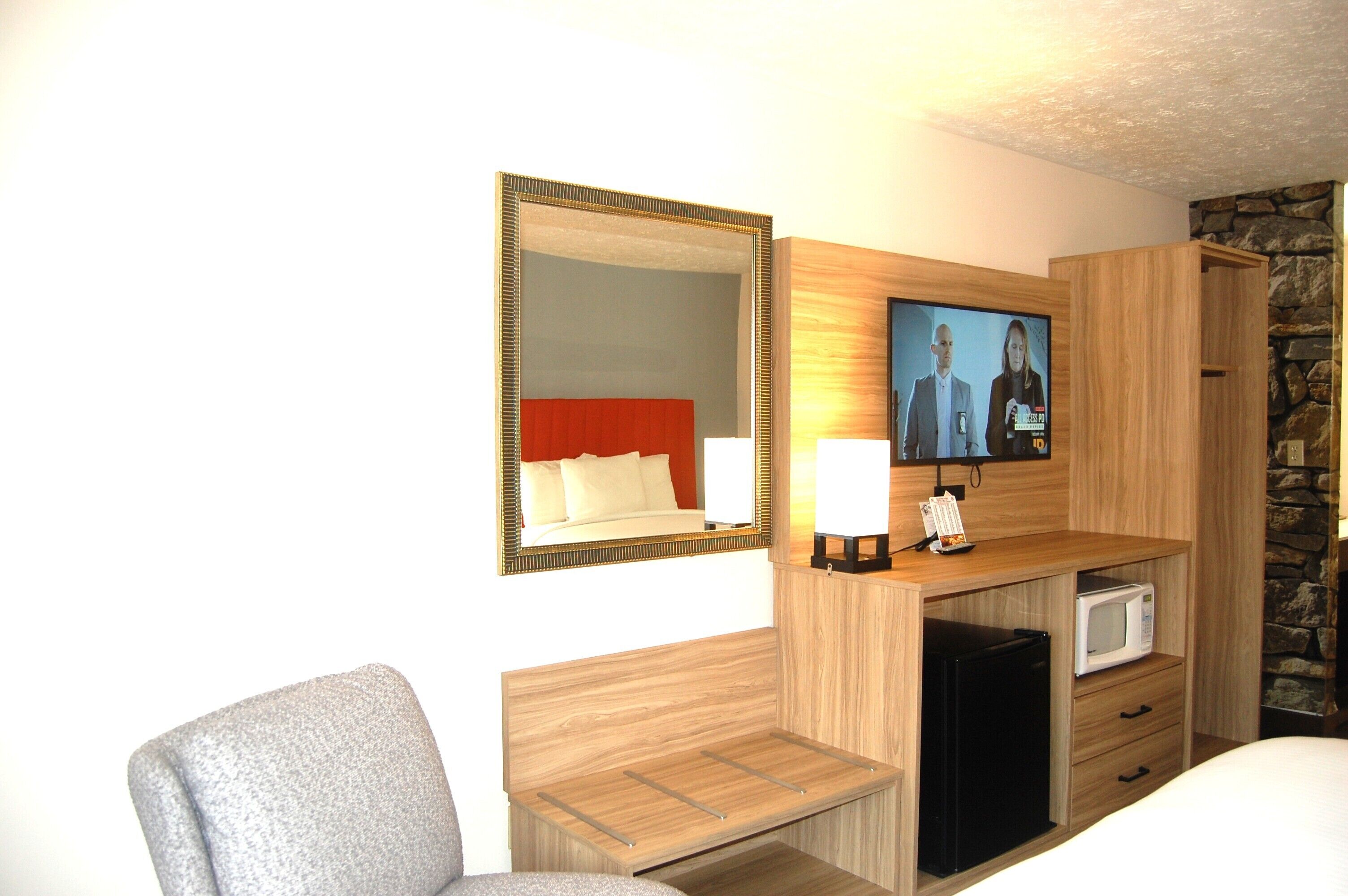 Une chambre d’hôtel équipée d’un lit, d’une télévision, d’un bureau avec une lampe, d’un four à micro-ondes et d’un petit réfrigérateur.