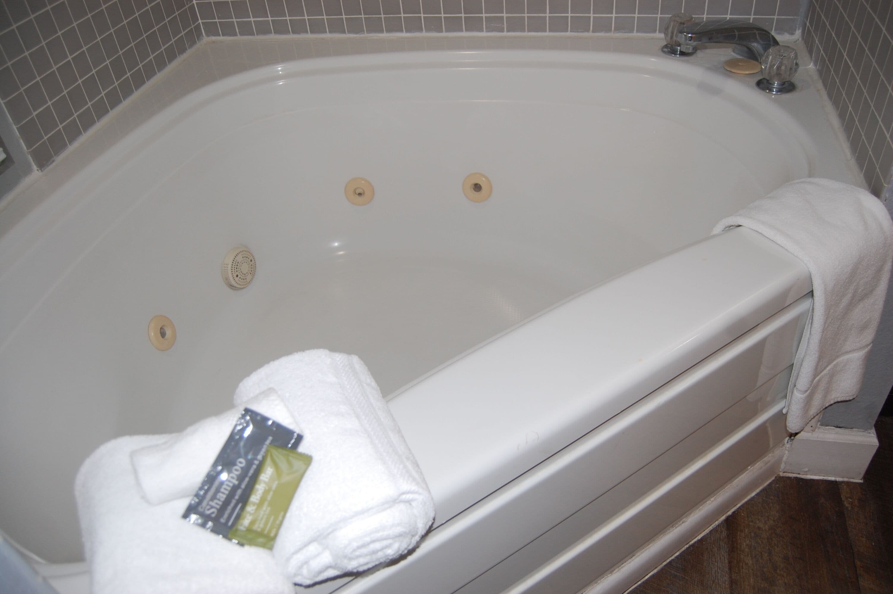 A white bathtub with a towel and shampoo bottle.
