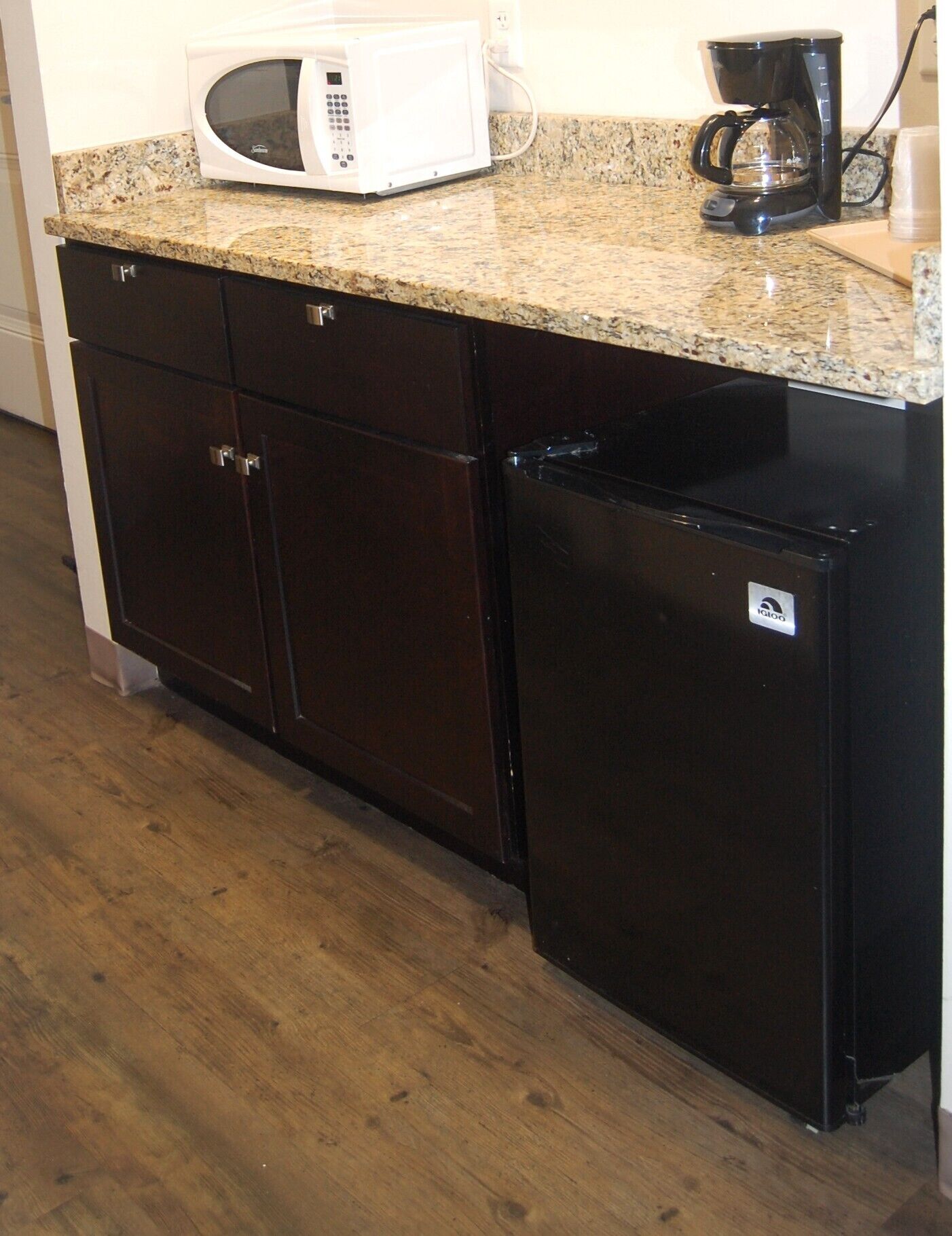 A kitchen with a microwave, coffee maker, and a refrigerator.