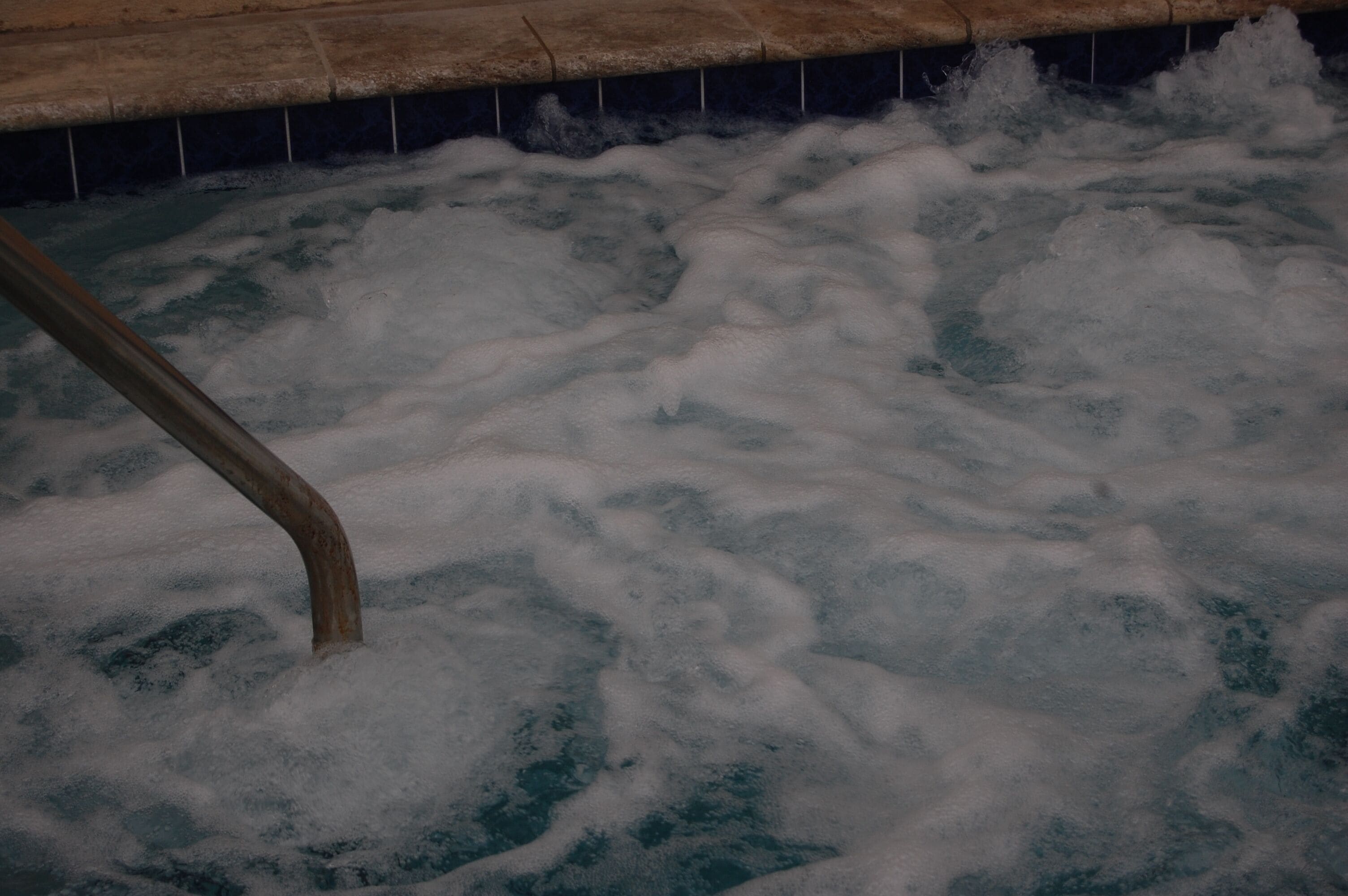 A hot tub with visible water jets and a metal railing.
