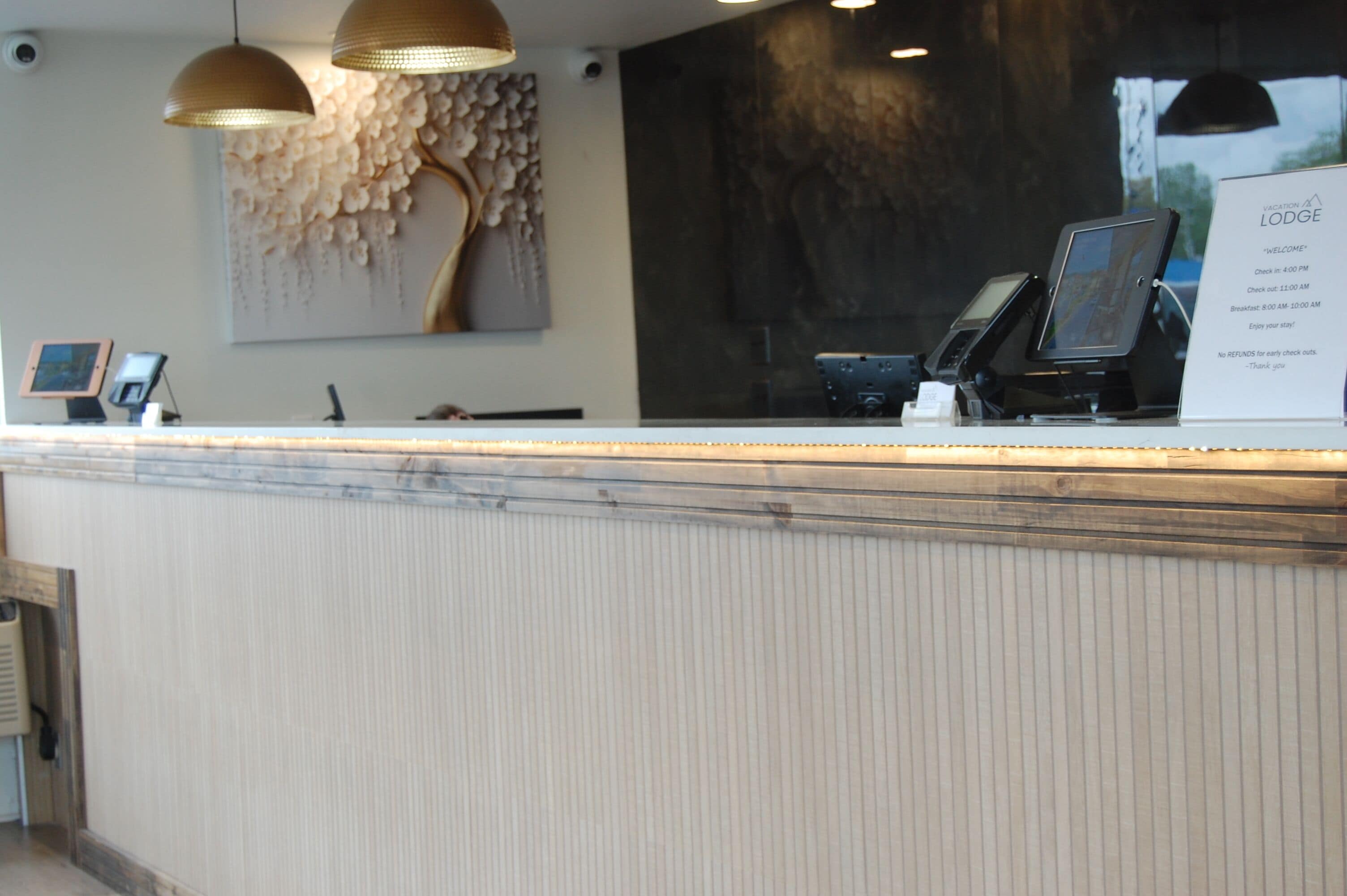 A reception desk with a check-in counter, a digital kiosk, and a wall-mounted sign with check-in times.