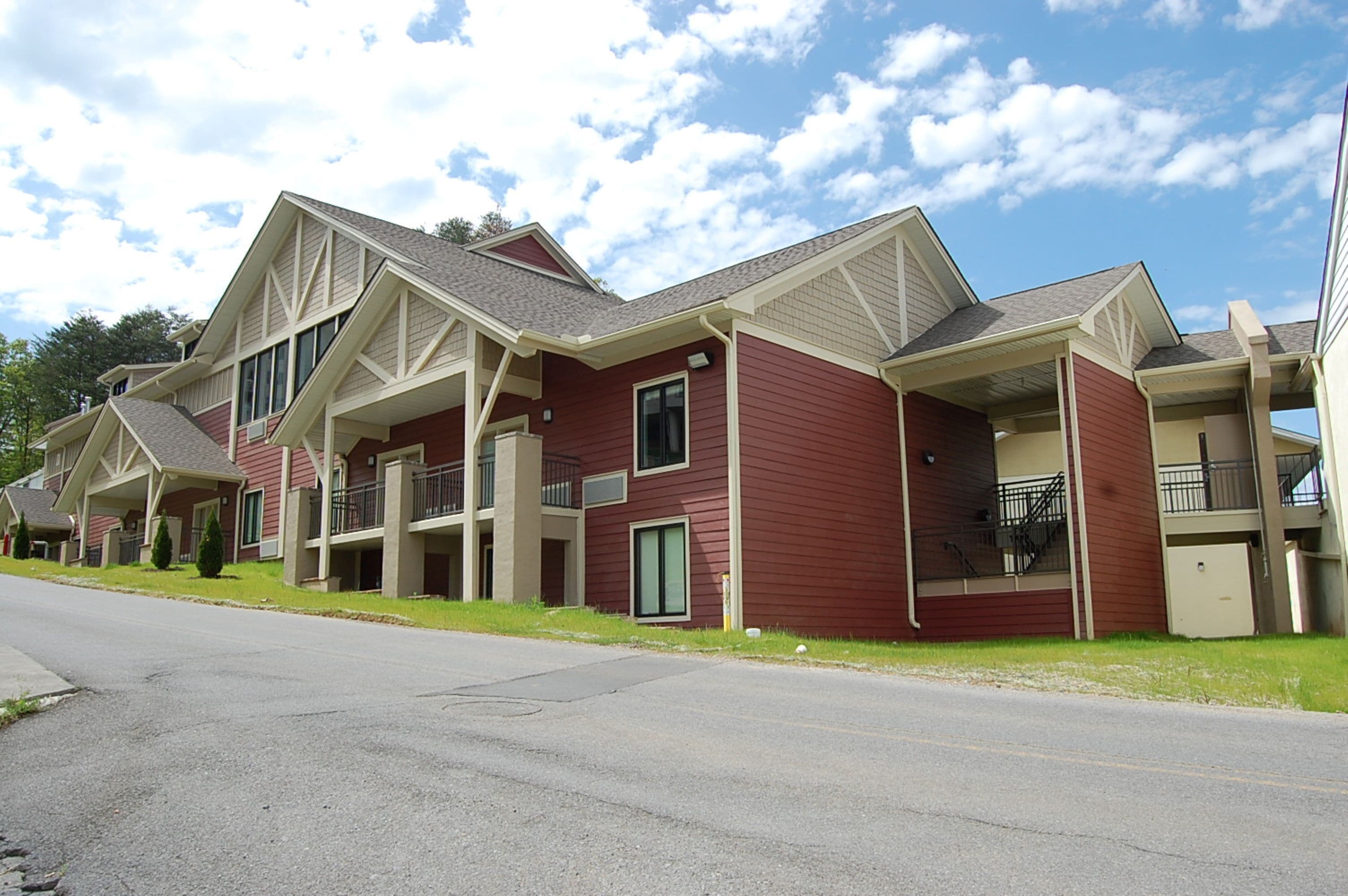 A row of red and beige multi-story buildings with balconies and a clear sky.