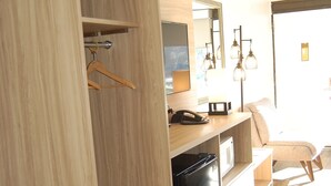 Una cocina moderna con armarios de madera, un lavavajillas negro y una encimera con un teléfono y un electrodoméstico pequeño.