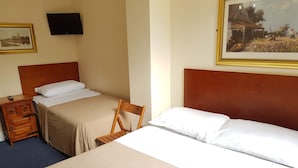A hotel room with two beds, a wooden nightstand, a chair, a flat-screen TV, and a framed painting on the wall. - Normandie Hotel (London)