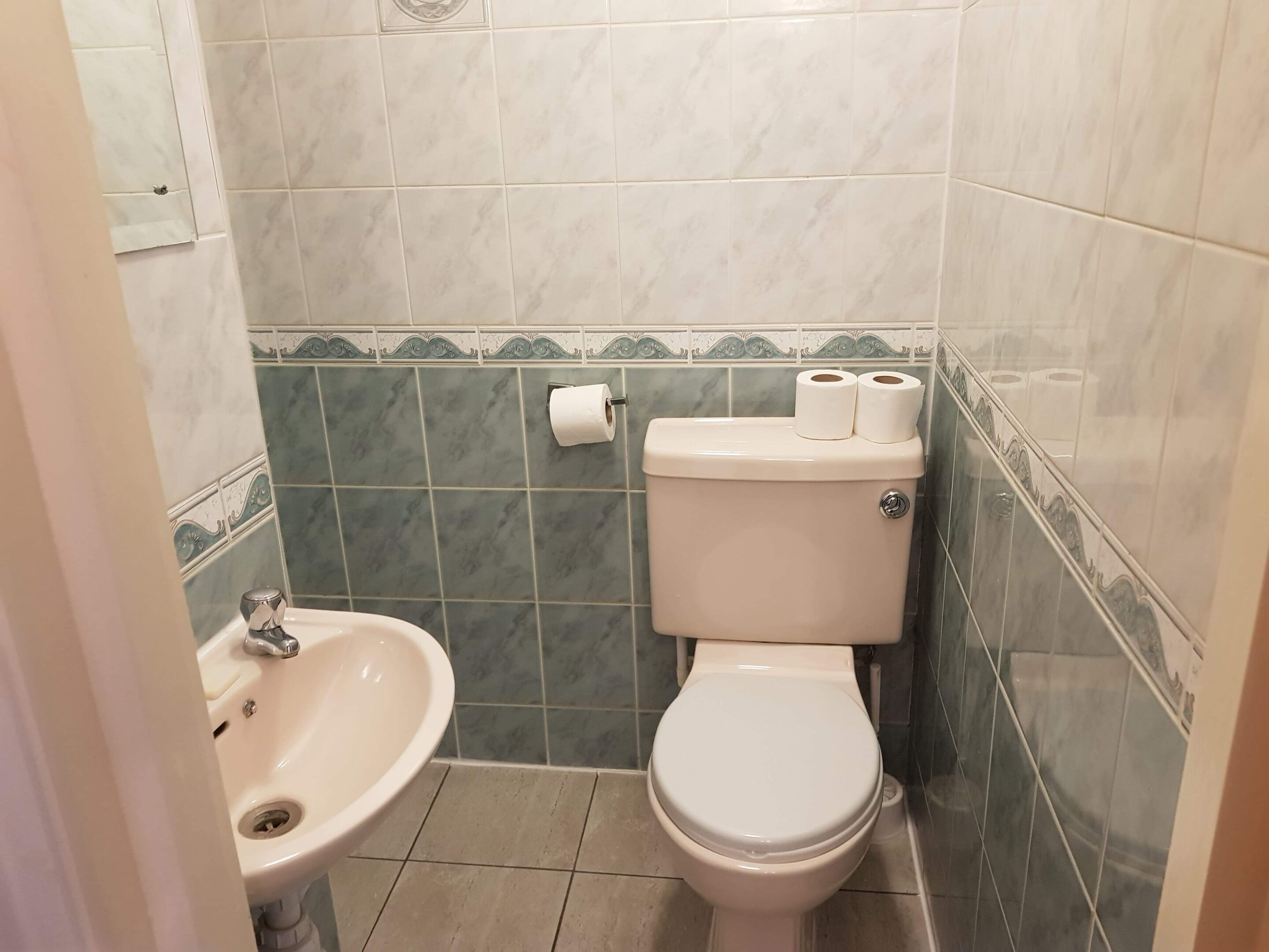 Une salle de bain équipée de toilettes, d’un lavabo et de carreaux décoratifs.