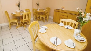 A dining area with a round wooden table and four chairs, a cabinet, and wall-mounted artwork. - Normandie Hotel (London)