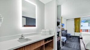 A modern hotel bathroom with a large mirror, a sink, and a vanity. - Holiday Shores (Myrtle Beach)