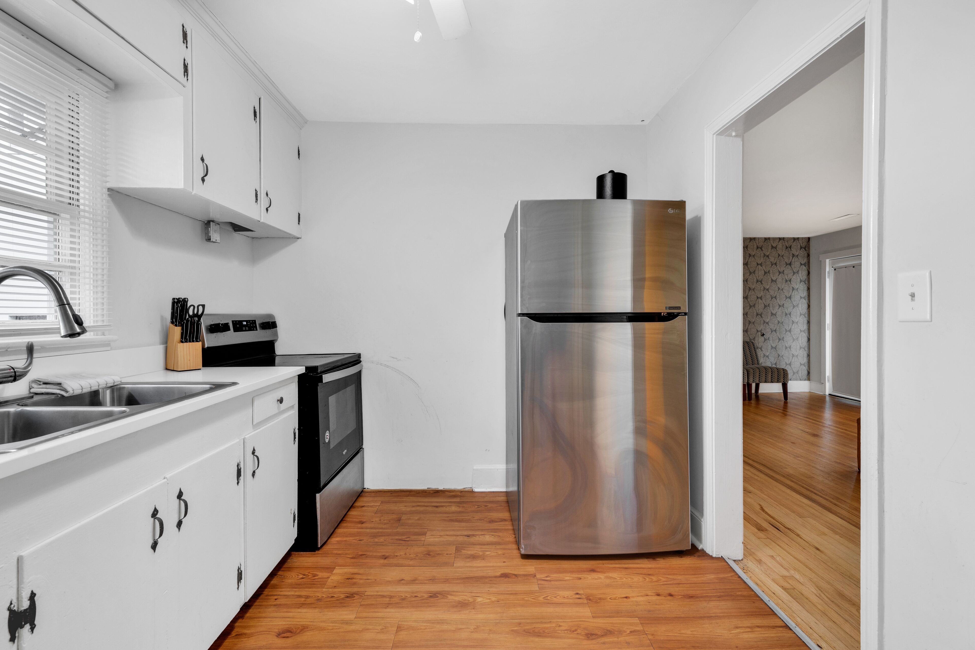 Una cocina moderna con armarios blancos, electrodomésticos de acero inoxidable y suelo de madera.