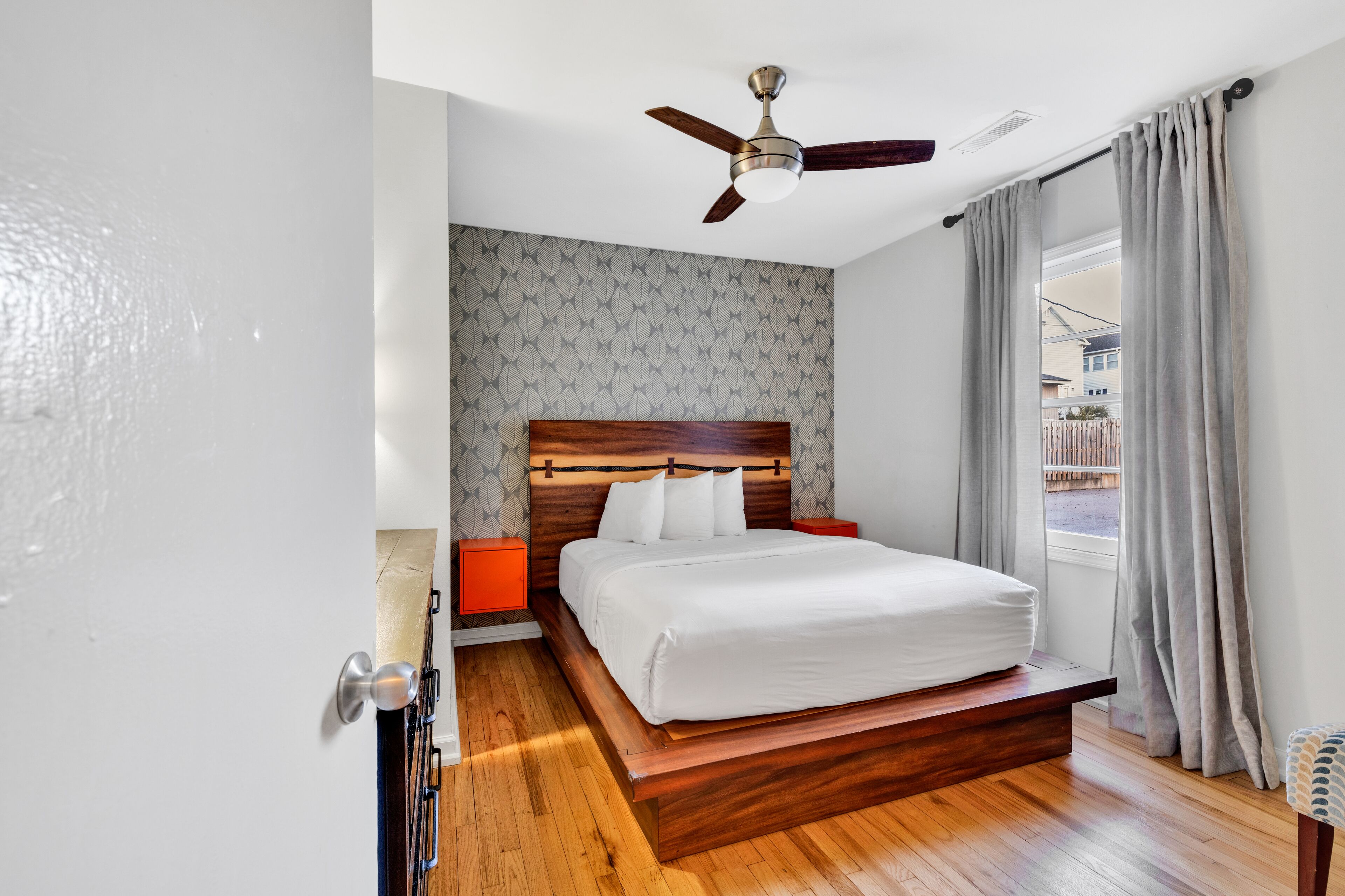 A bedroom with a wooden bed, a ceiling fan, and a window with curtains.
