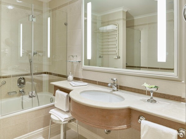 A modern bathroom with a glass-enclosed shower, a large mirror, and a beige vanity with a sink and towel rack.