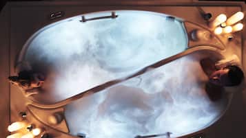 Un jacuzzi grande y ovalado con dos personas adentro.