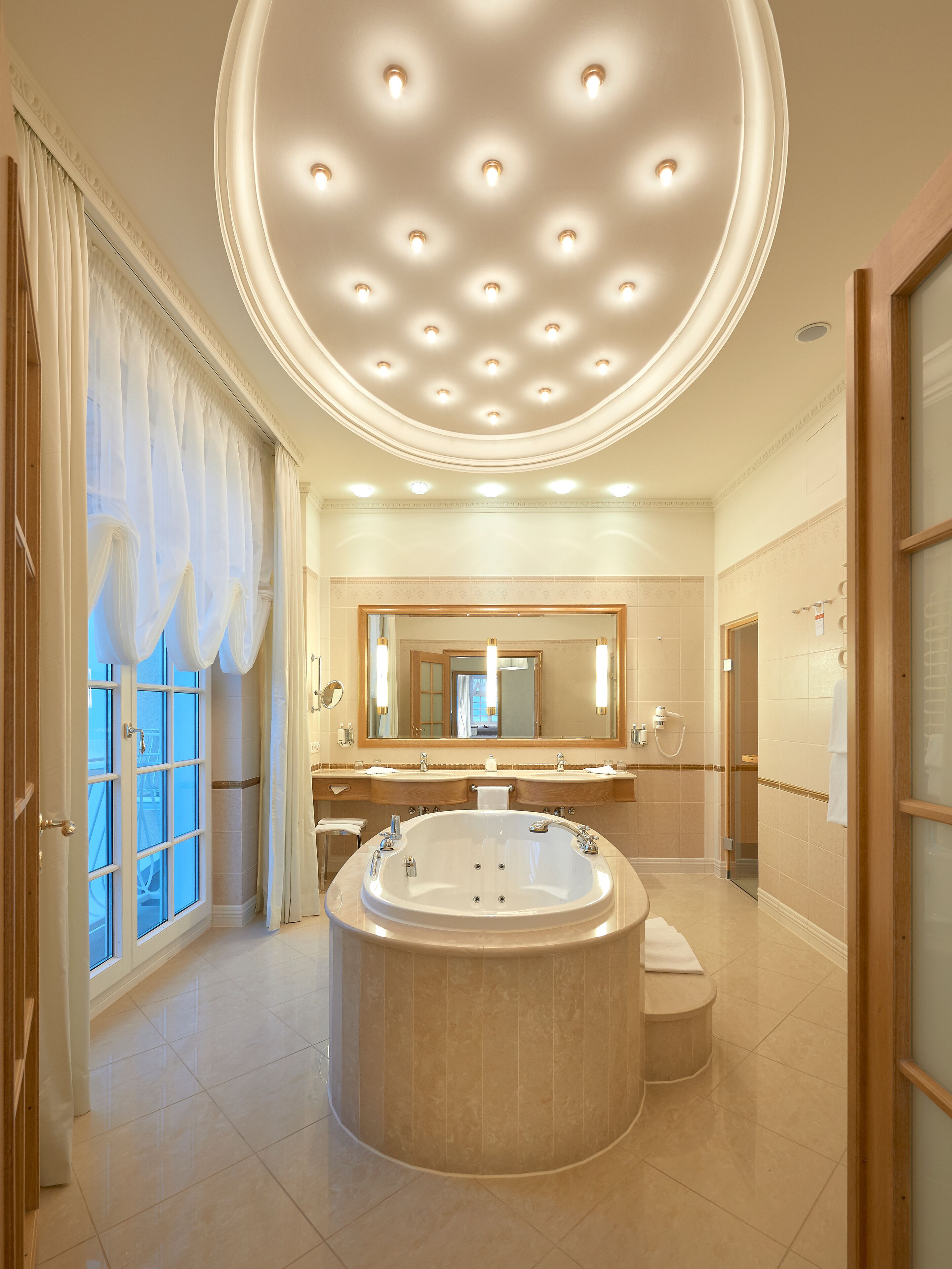 Un baño espacioso con una bañera grande, un lavamanos doble, un espejo amplio e iluminación empotrada en el techo.