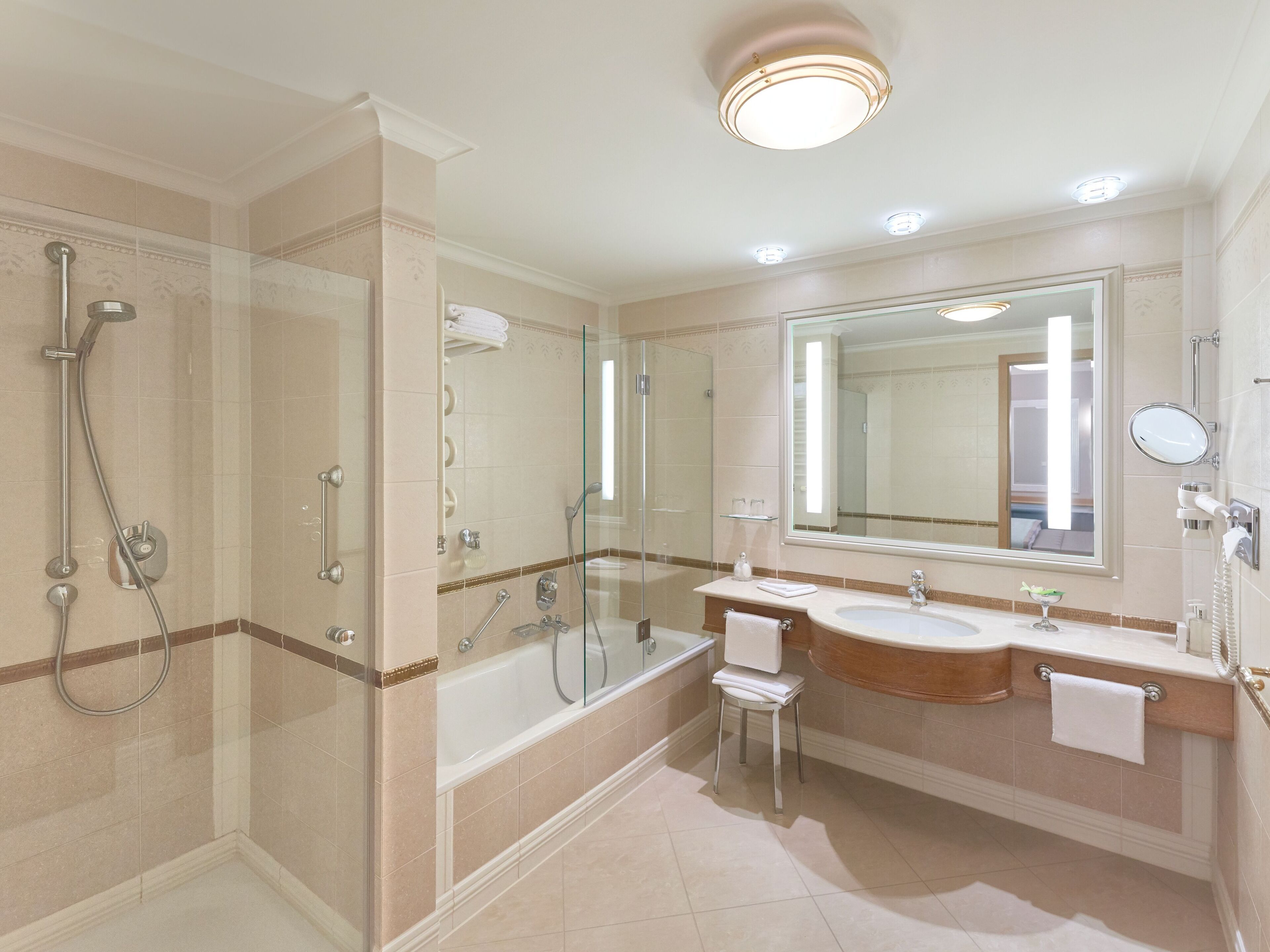 Un baño moderno con ducha de vidrio, bañera y tocador con un espejo grande.