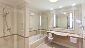 Un baño moderno con ducha de vidrio, bañera y tocador con un espejo grande.