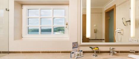 A bathroom with a large window, a sink, a mirror, and a towel rack.