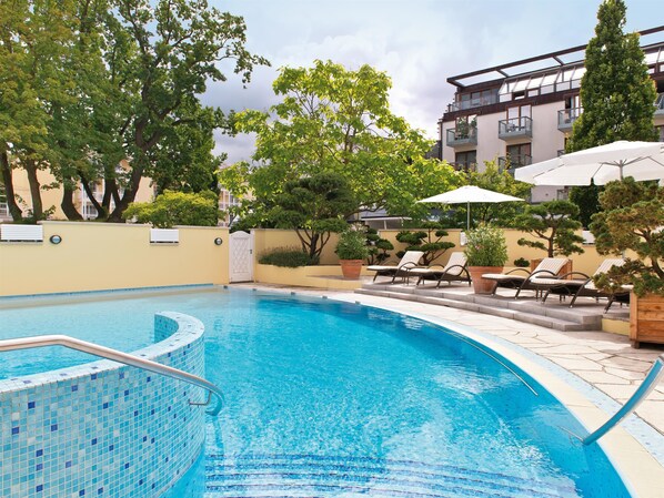 Alberca techada, alberca al aire libre y sombrillas en la alberca