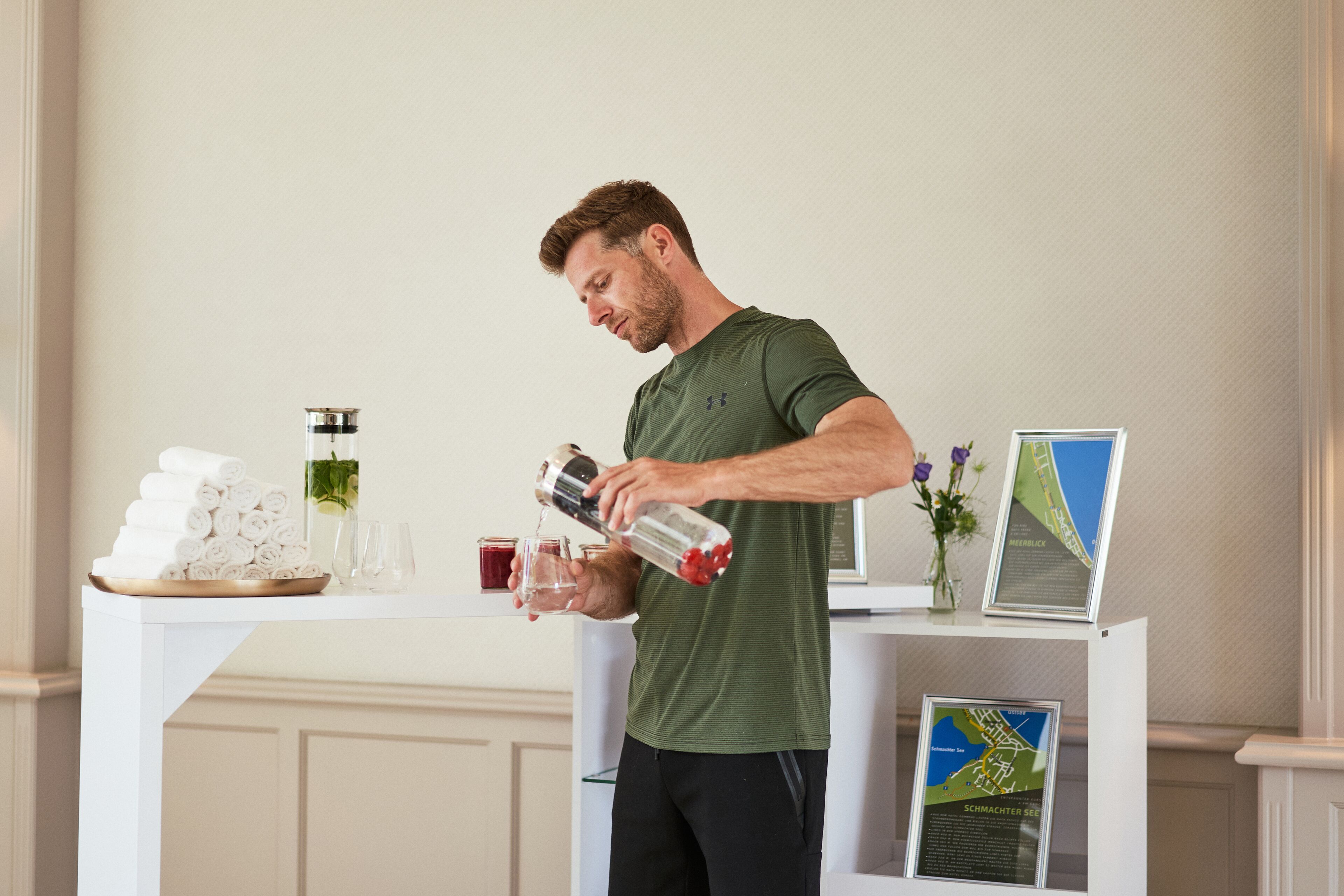 Un homme verse une boisson dans un verre sur un comptoir blanc, à côté duquel se trouvent des serviettes enroulées et une carte.