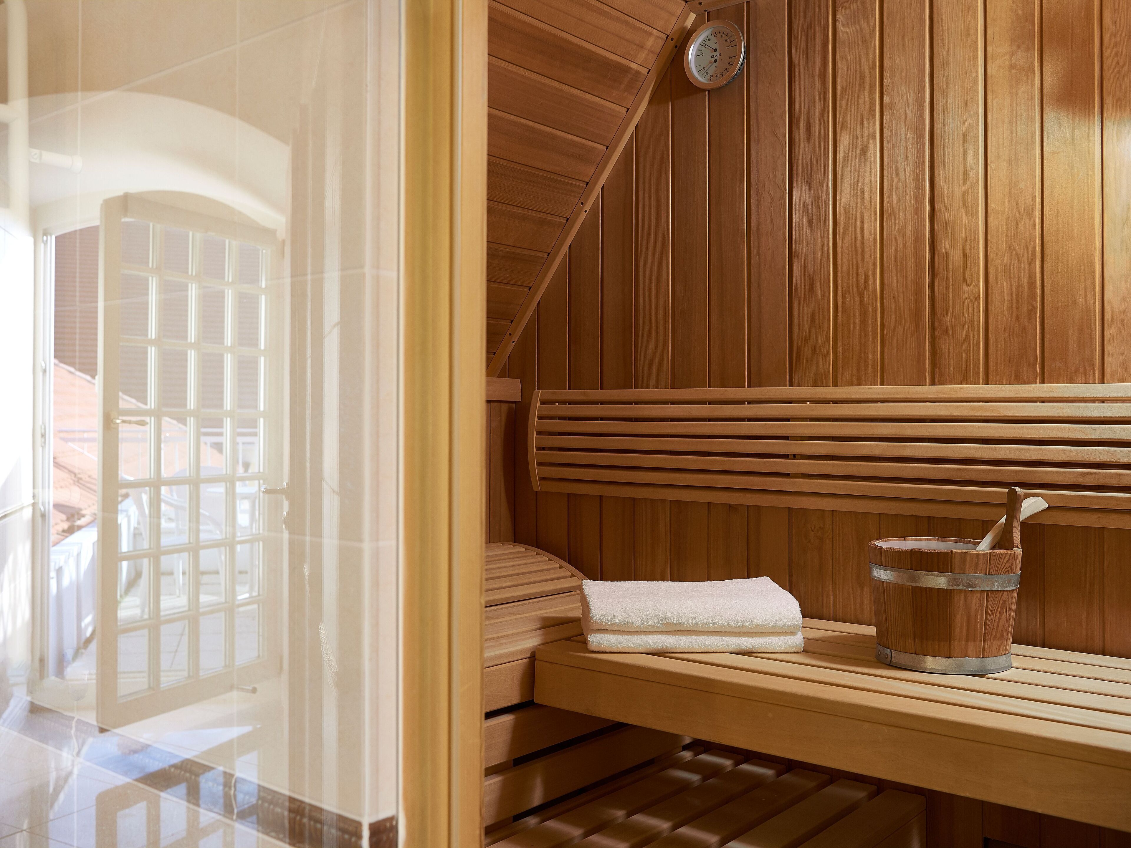 A sauna with wooden benches, a towel, and a bucket with a wooden spoon.