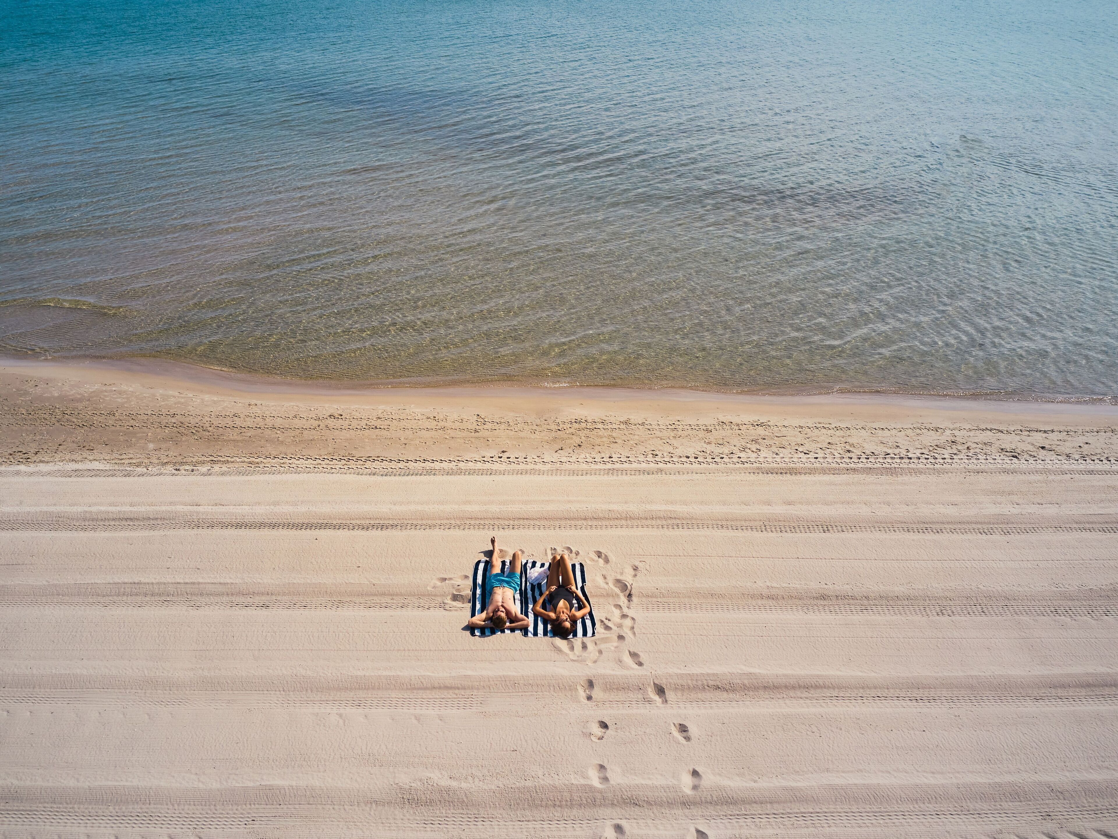 Une plage offrant une vue dégagée sur l’océan et une zone sablonneuse parsemée d’empreintes.