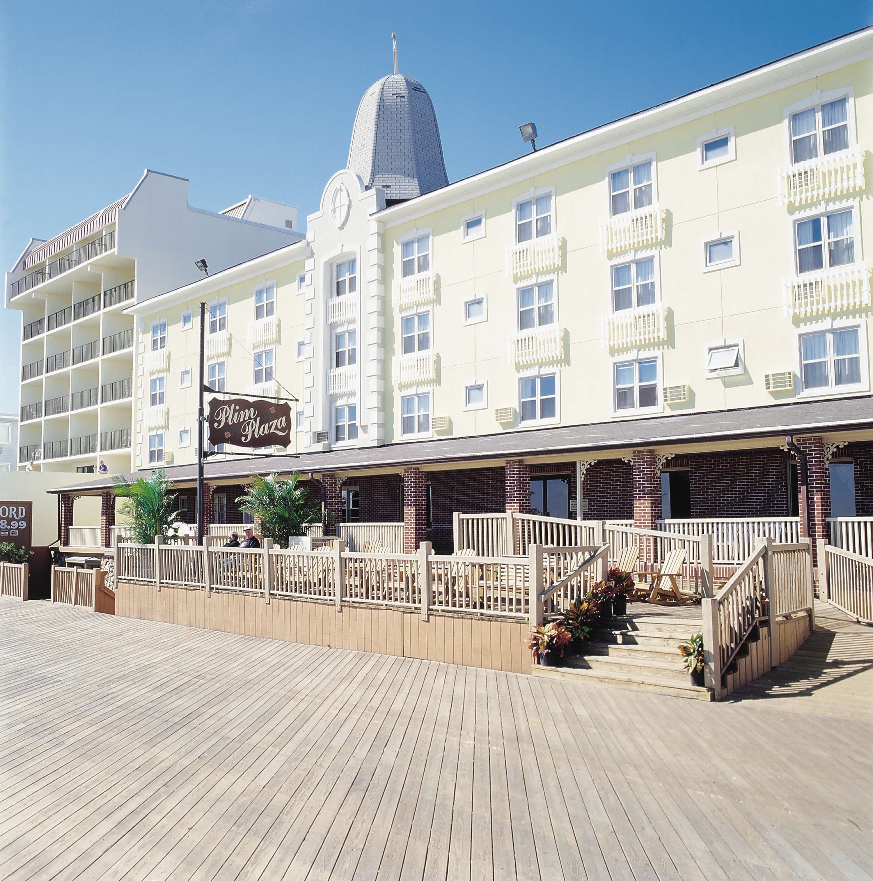 Un hotel con una cúpula destacada, varios balcones y un paseo marítimo de madera que conduce a la entrada.