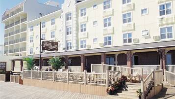 Un hotel con una cúpula destacada, varios balcones y un paseo marítimo de madera que conduce a la entrada.