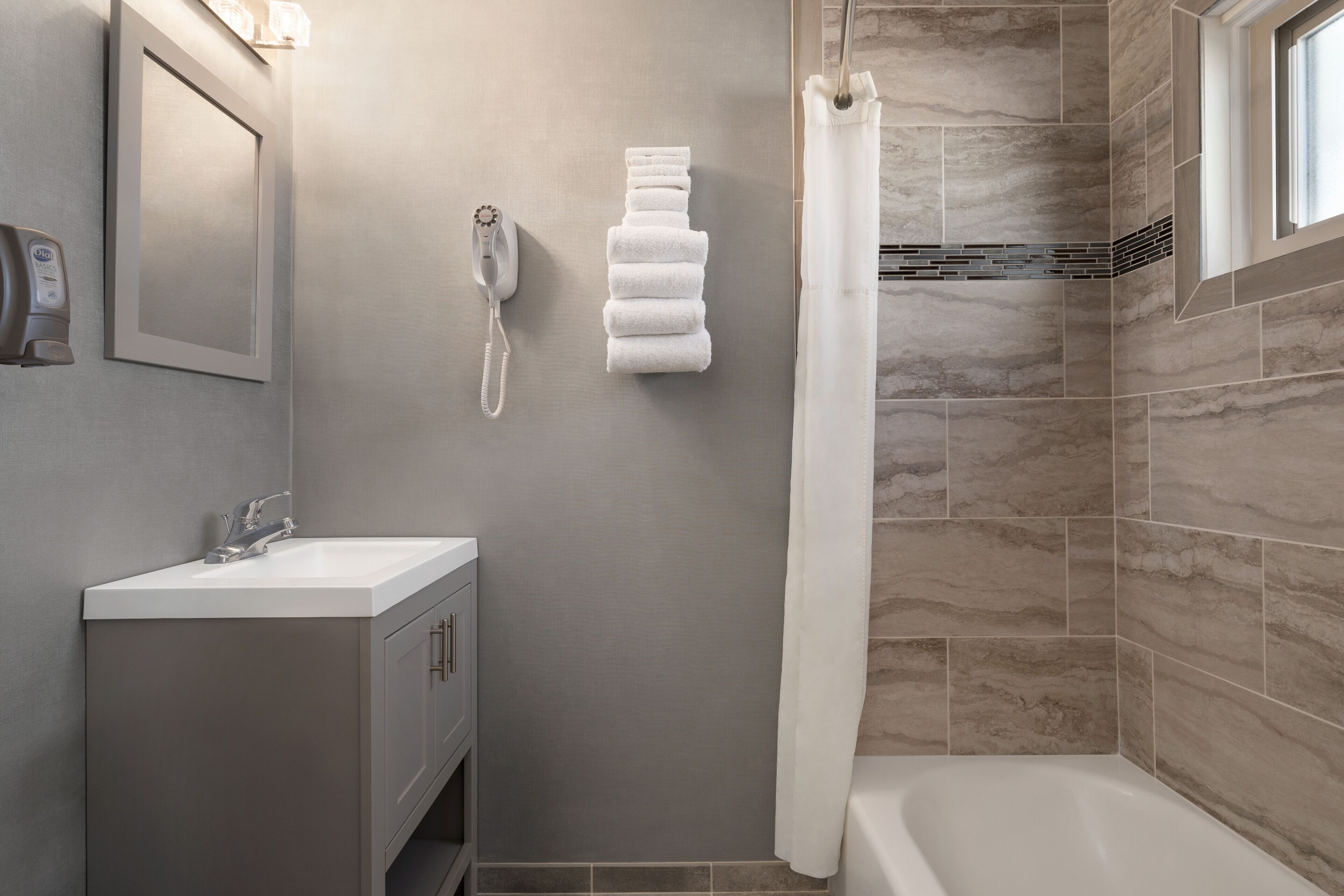 A modern bathroom with a sink, mirror, towel rack, shower curtain, and a bathtub.