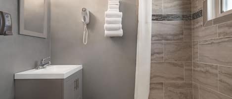 A modern bathroom with a sink, mirror, towel rack, shower curtain, and a bathtub.