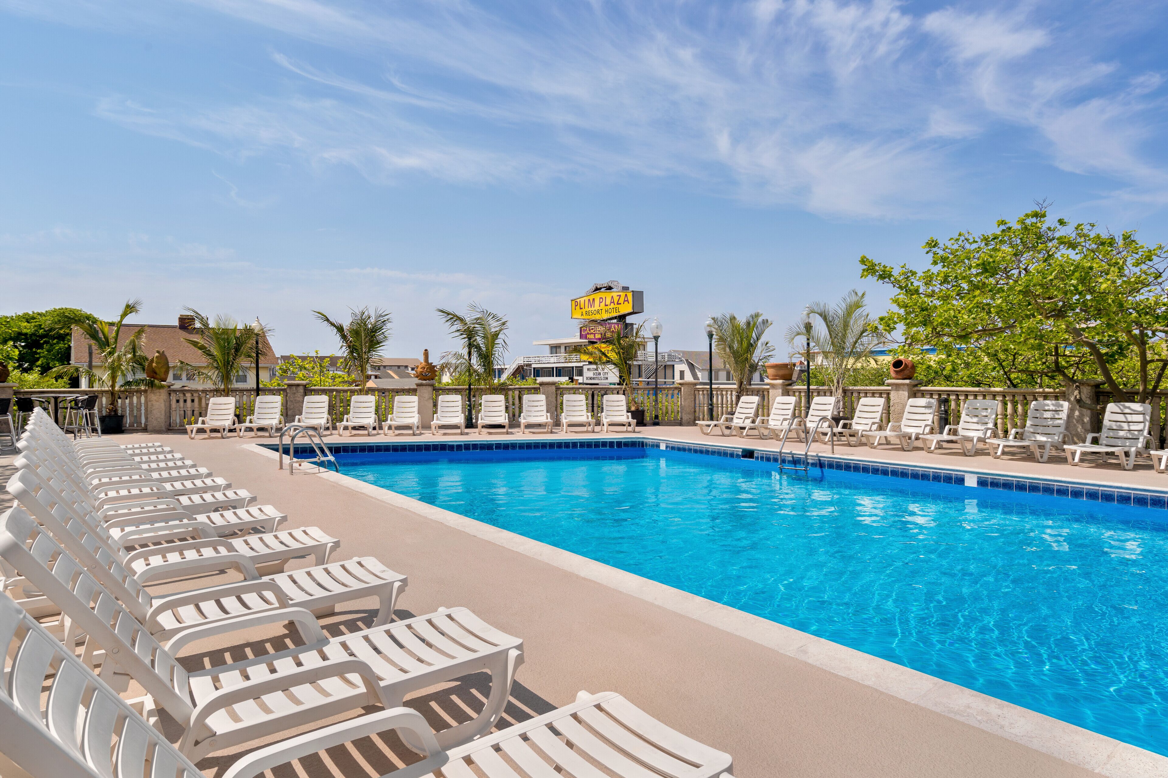 A swimming pool with lounge chairs and a sign for 'Plim Plaza Resort Hotel'.