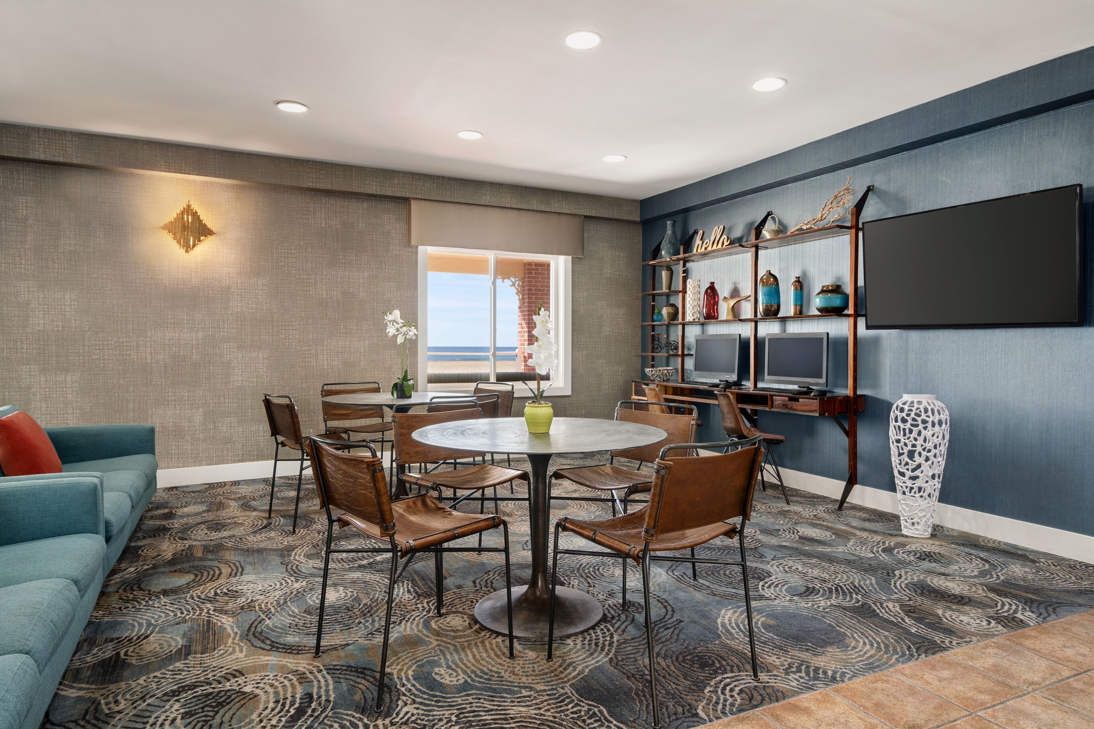 A modern living room with a round table, chairs, a sofa, and a TV mounted on the wall.